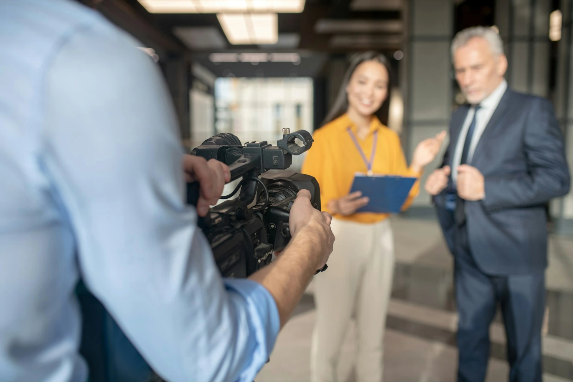 Camarógrafo grabando a una reportera entrevistando a un ejecutivo.